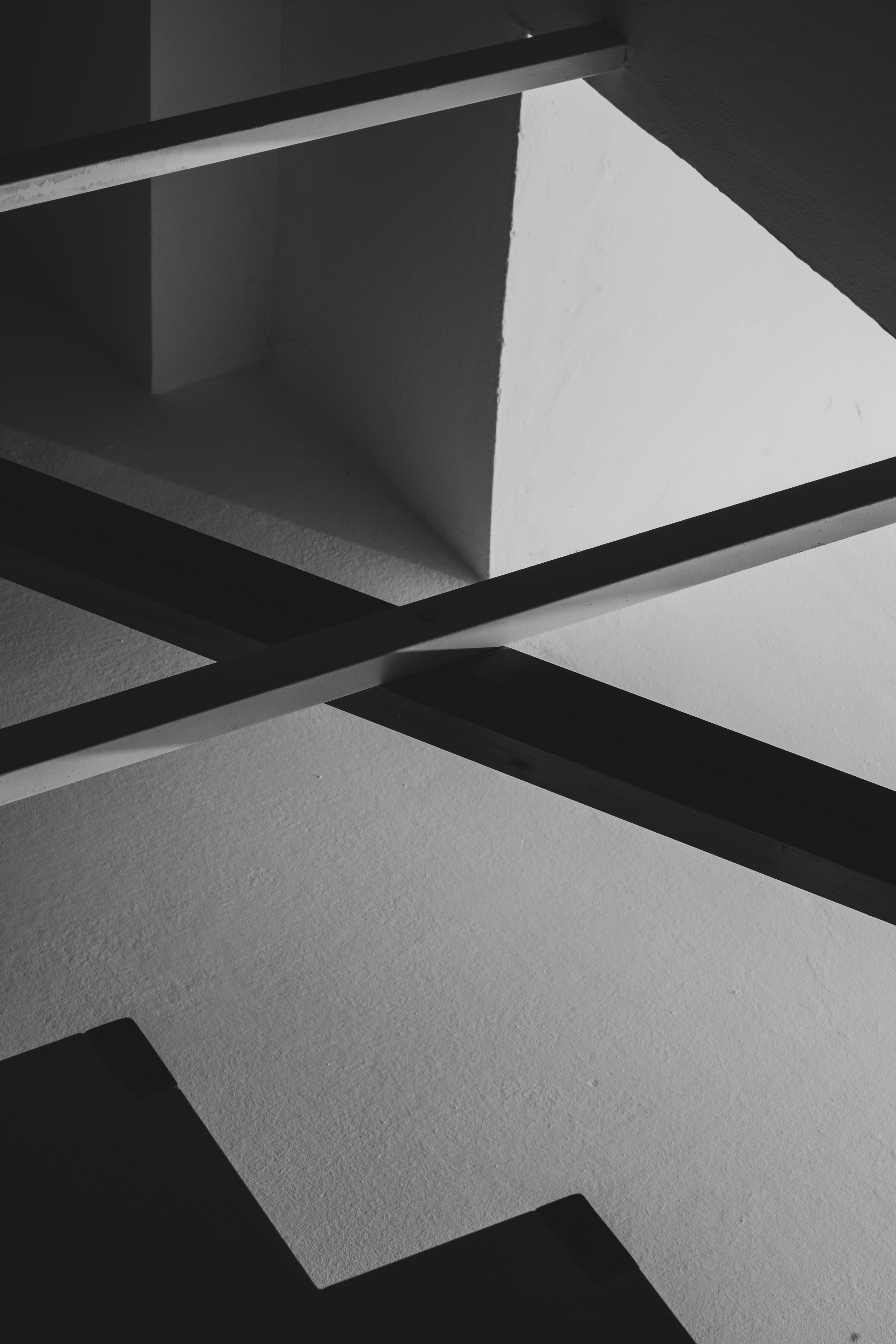 Black-and-white study of crossed staircase shadows against a stark wall