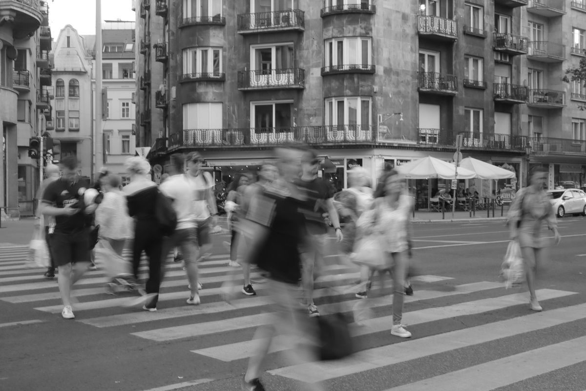 Long-exposure black-and-white photo of a crowd blurring across a city crosswalk