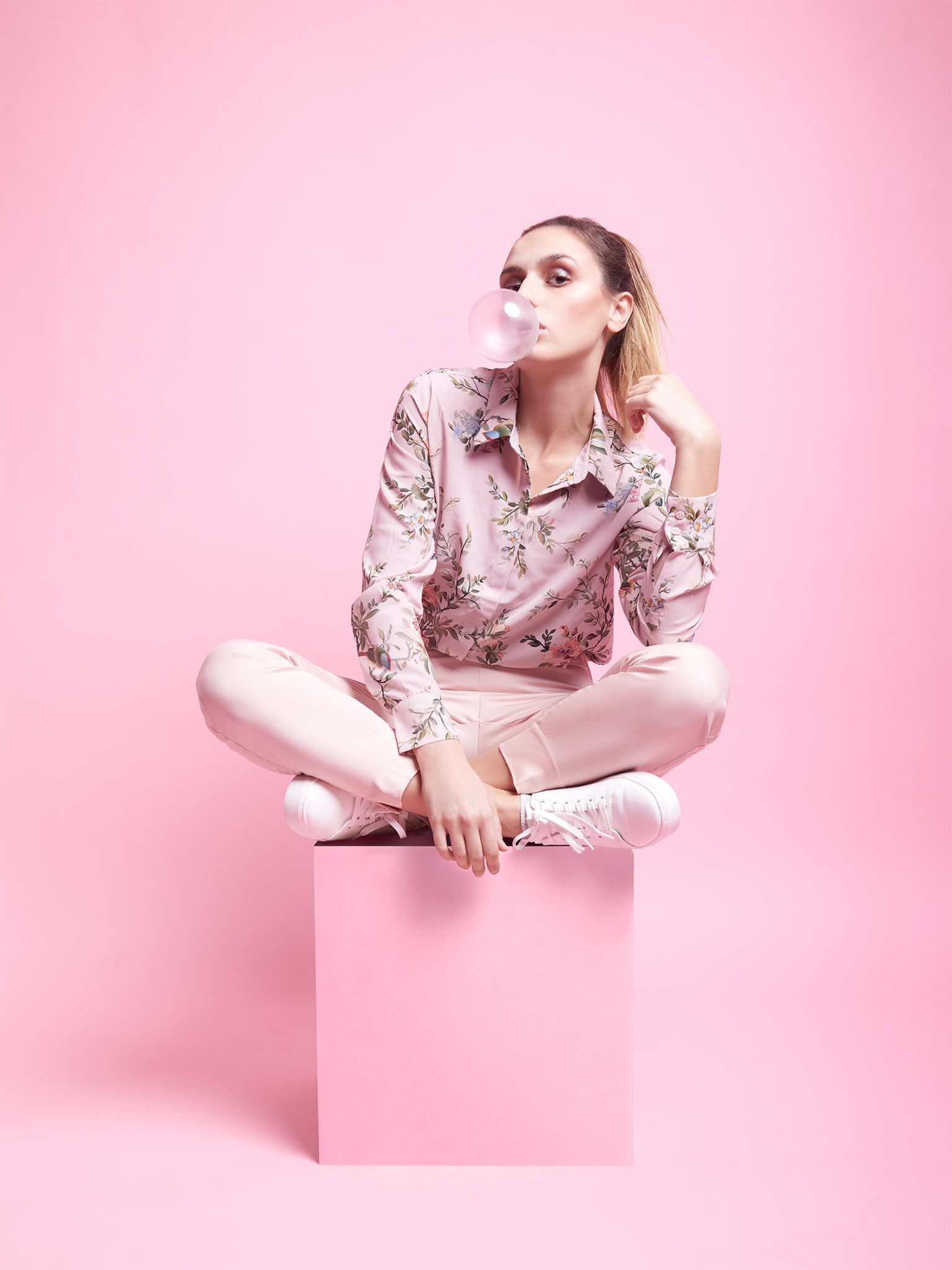 Editorial fashion portrait in monochrome pink, blowing a bubblegum bubble