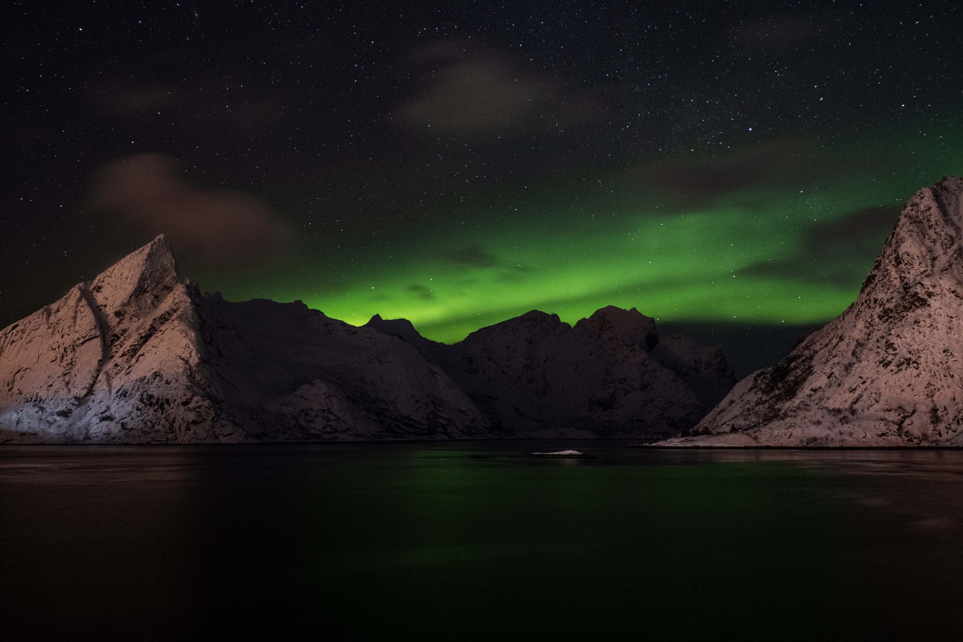 The aurora borealis glowing green over a mountain landscape