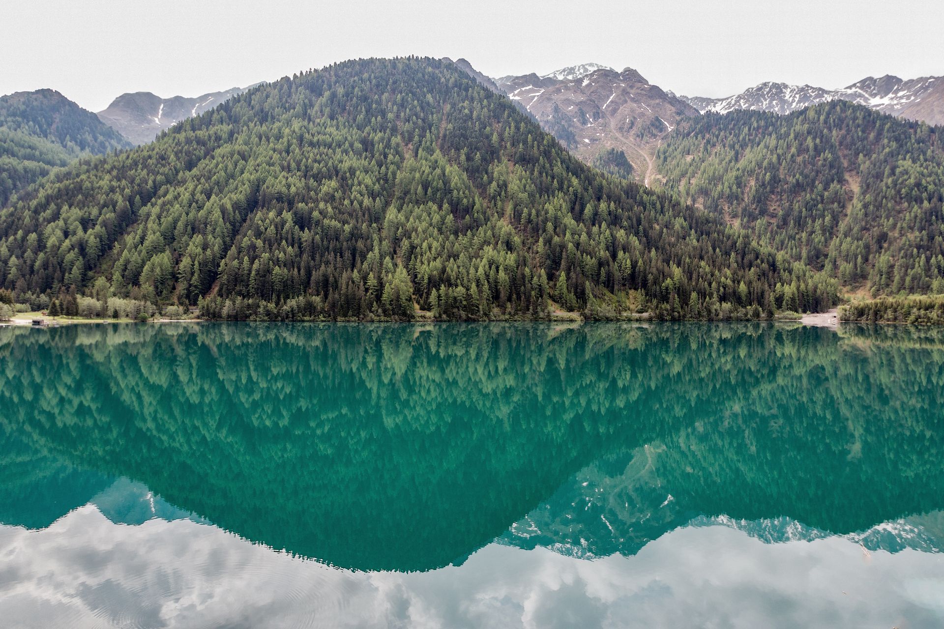 A calm alpine lake with a mirror-still reflection of the mountains above it