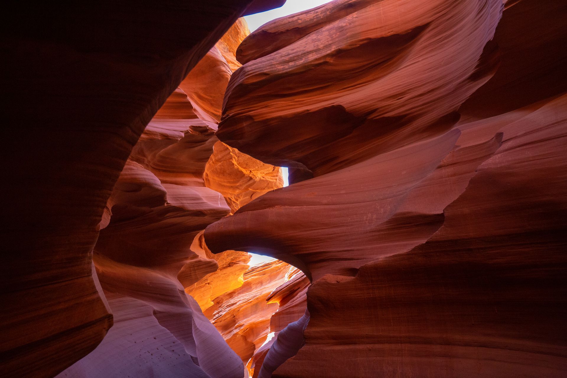 A narrow slot canyon with warm glowing sandstone walls and light beams