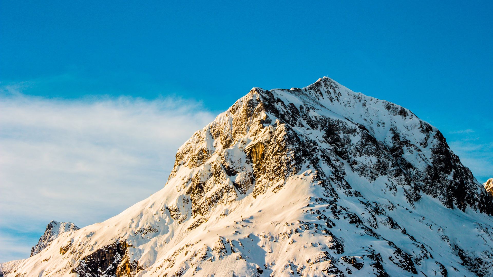 A single dramatic snow-capped mountain peak against a clear sky
