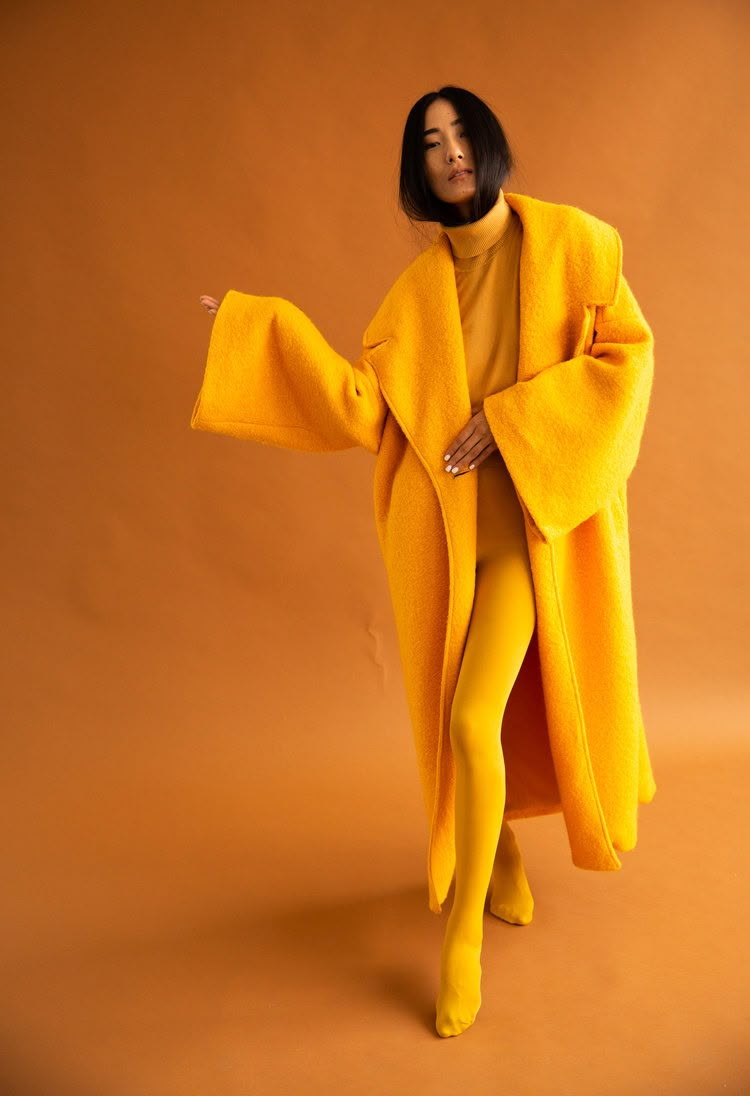 Editorial fashion portrait in monochrome mustard-gold, oversized coat